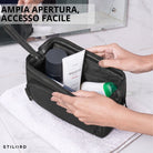 Necessaire Henry in pelle nera, ampio scomparto aperto, interno con prodotti da bagno e mani sopra asciugamano