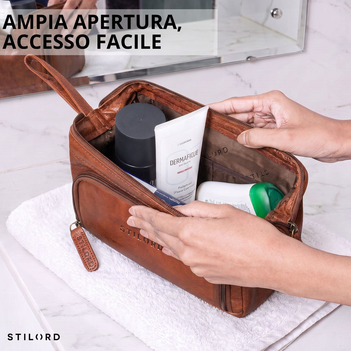 Beauty case in pelle marrone maraska con ampia apertura, mani tengono il vano principale aperto e interno visibile