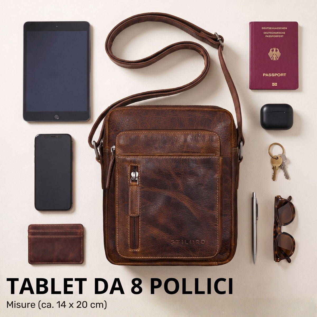 Kleine braune Rindsleder-Schultertasche mit STILORD Prägung, frontal neben Tablet, Reisepass und Accessoires